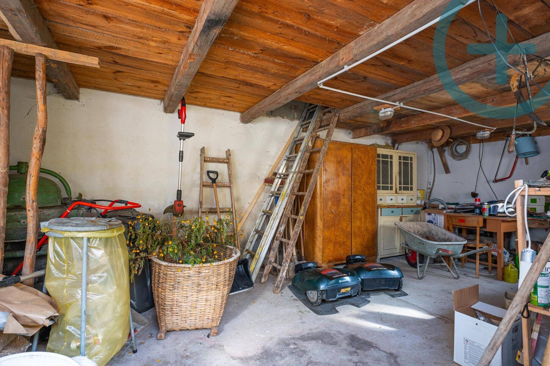 Geräumiger Werkstatt- und Lagerraum mit Holzbalkendecke und verschiedenen Geräten.