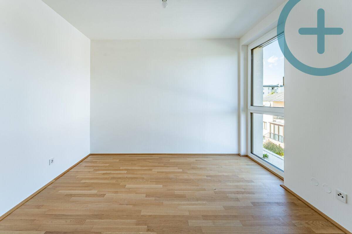 Helles Zimmer mit Parkettboden und großem Fenster, ideal als Kinderzimmer oder Büro.