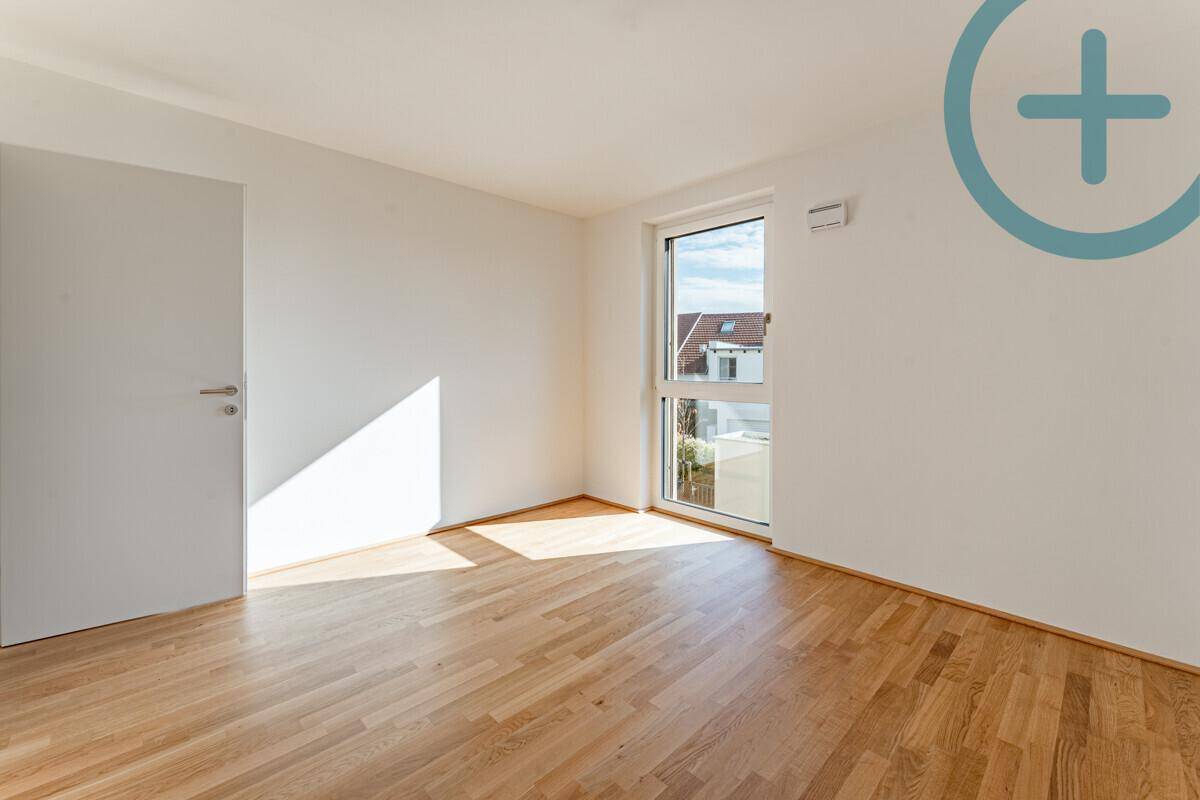 Sonniger Raum mit Parkettboden und großem Fenster, ideal als Schlaf- oder Arbeitszimmer.