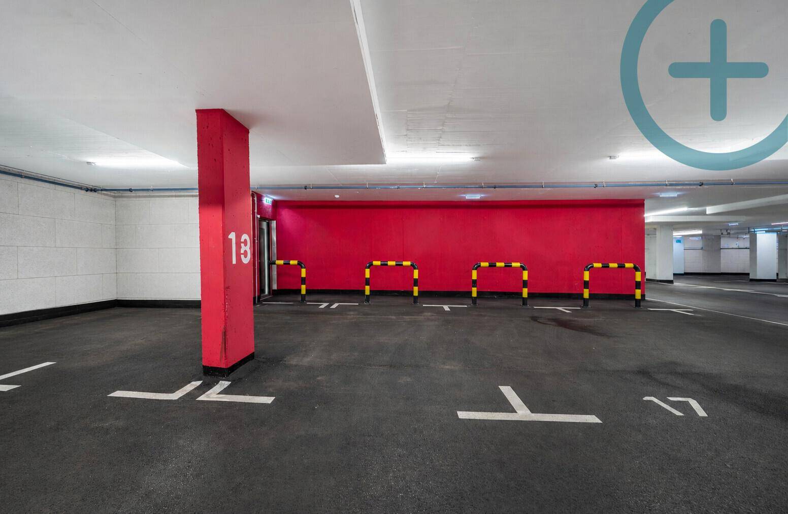 Heller Tiefgaragenstellplatz mit nummerierter Säule und farbiger Wandgestaltung.