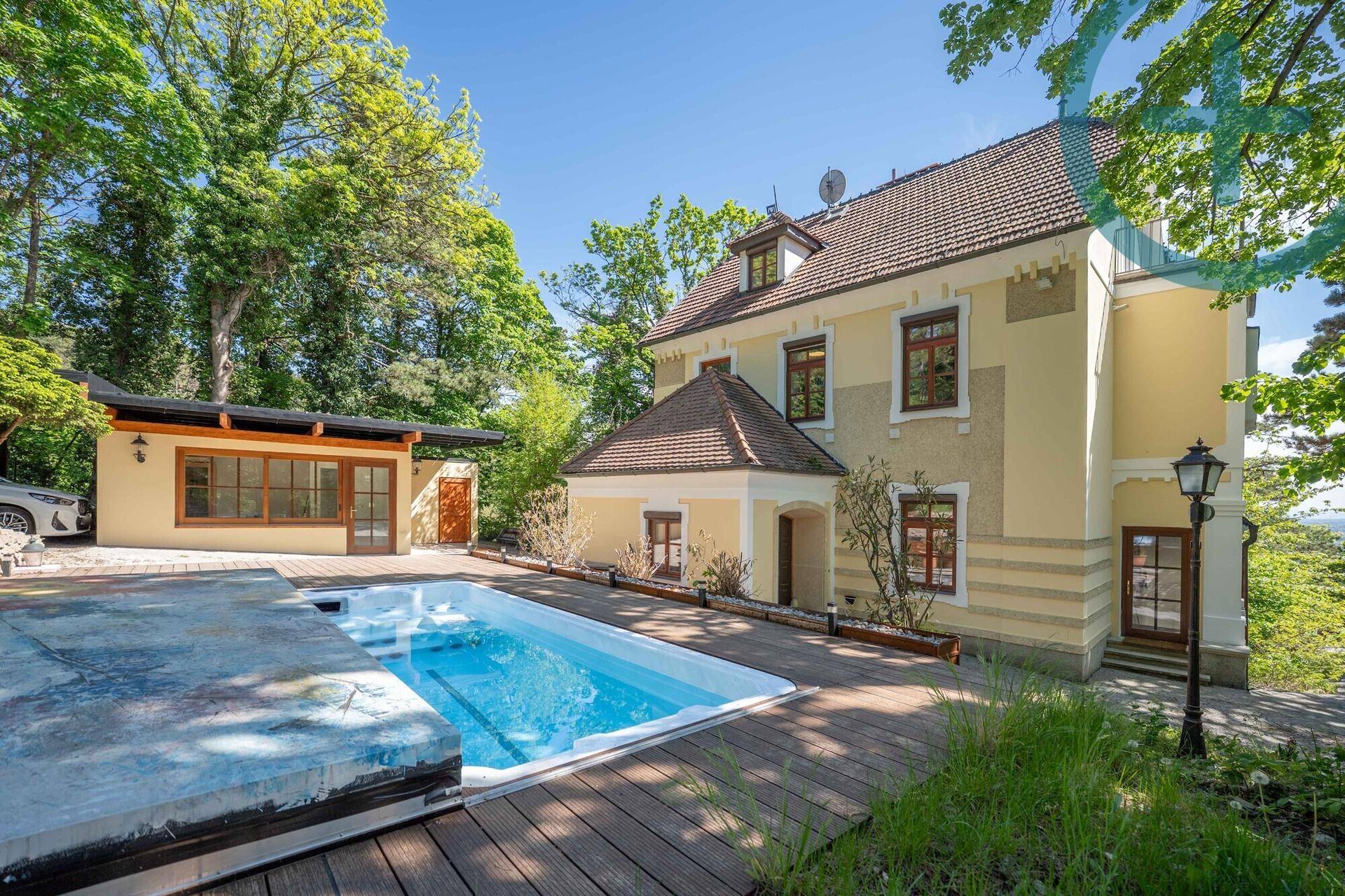 Elegante Villa mit Außenpool und Holzdeck, umgeben von altem Baumbestand.