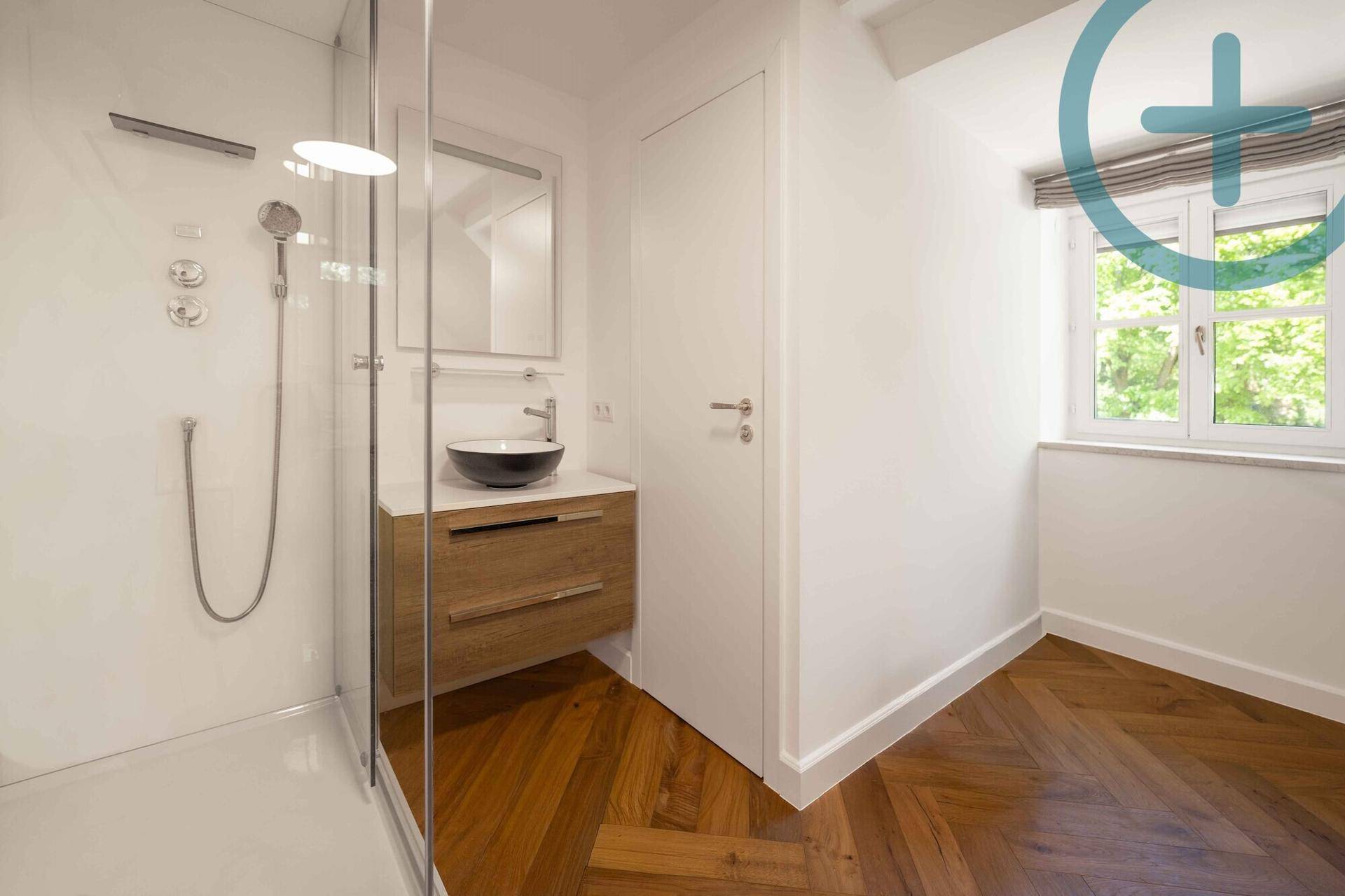Modernes Badezimmer mit begehbarer Dusche, Holzwaschtisch und Fenster im Dachgeschoss.