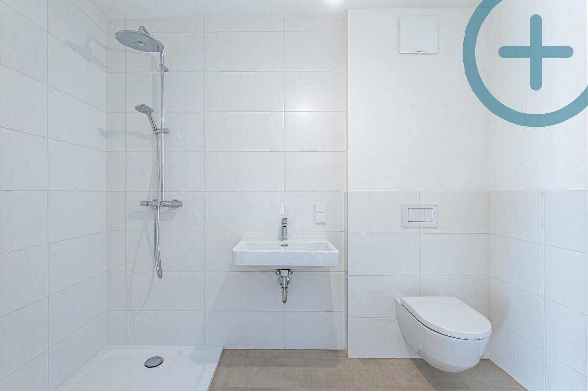 Modernes Badezimmer mit ebenerdiger Dusche, wandhängendem WC und Einzelwaschbecken in Weiß.