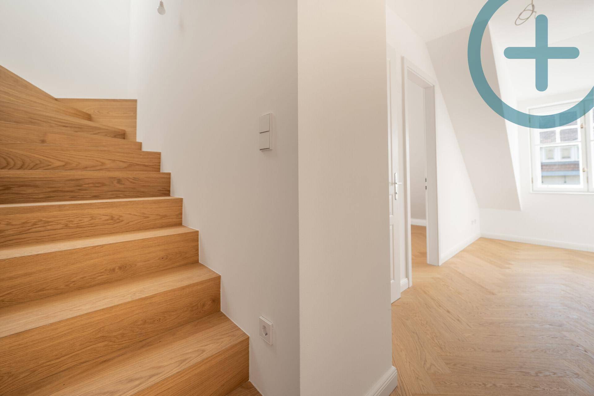 Moderne Holztreppe führt zu den oberen Etagen mit hellem Fischgrätparkett.