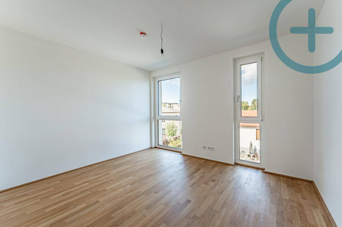 Geräumiges Schlafzimmer mit Parkettboden und viel Tageslicht durch zwei Fenster.