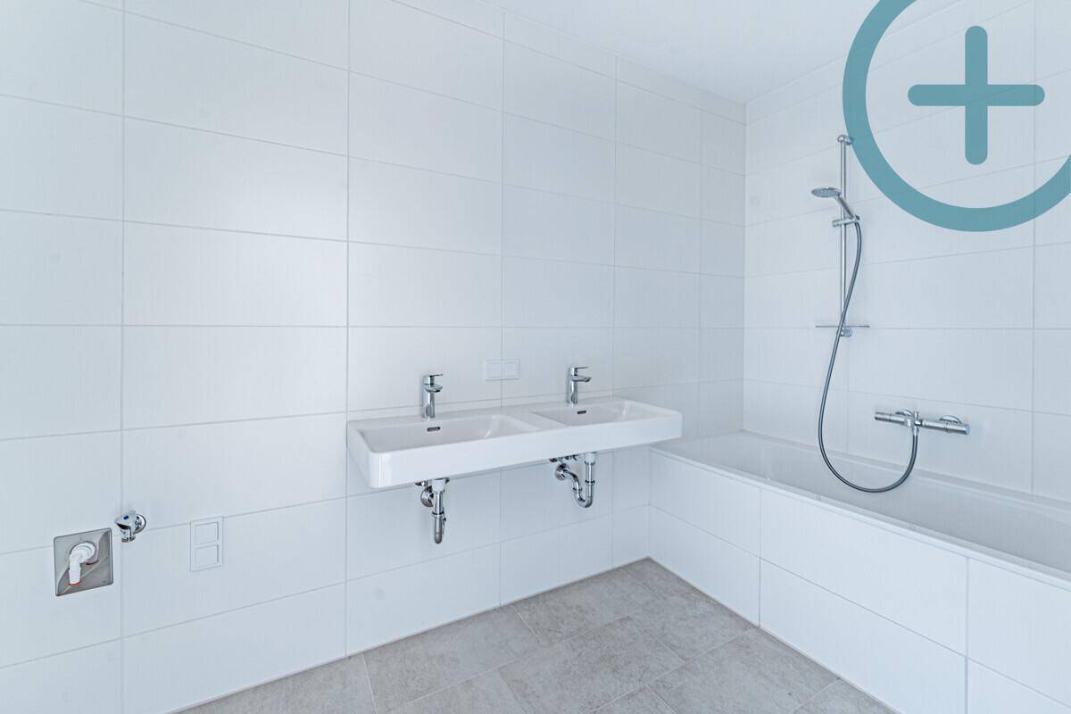 Modernes Badezimmer mit weißen Fliesen, Doppelwaschbecken und Badewanne mit Duschfunktion.
