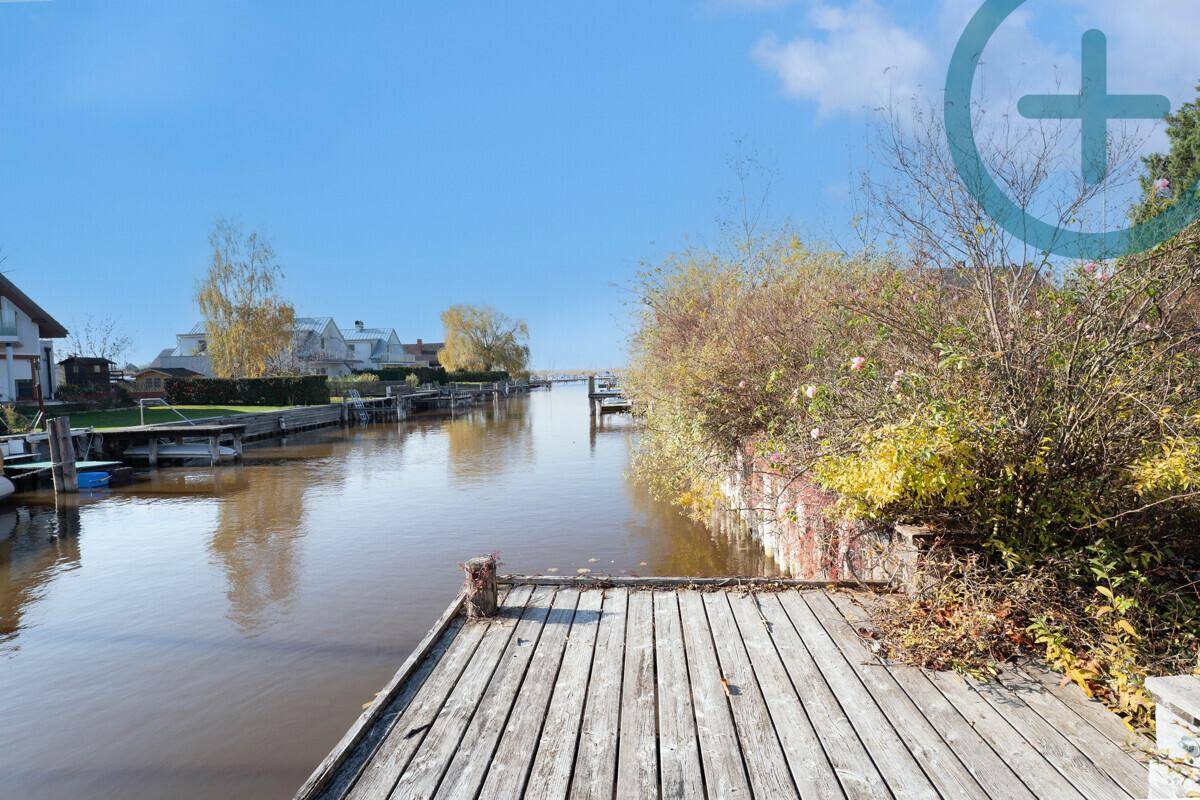 Hölzerner Bootssteg am Kanal mit Blick auf die umliegenden Häuser und die Wasserlandschaft.