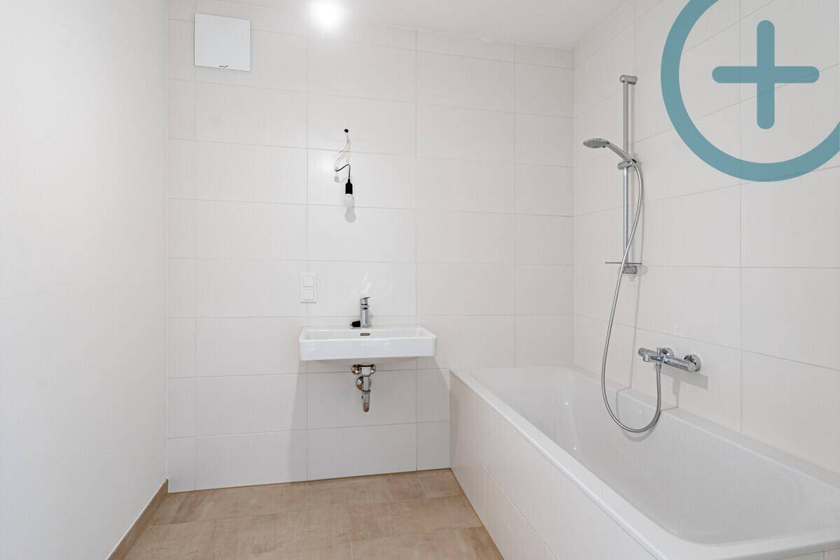 Modernes Badezimmer mit Badewanne, Waschbecken und Duschfunktion in hellen Fliesen.