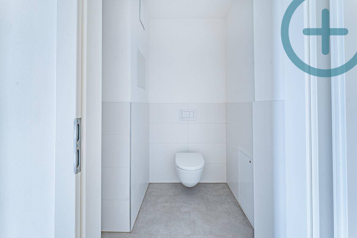 Sauberes Gäste-WC mit weißen Wandfliesen und einem modernen wandhängenden WC.