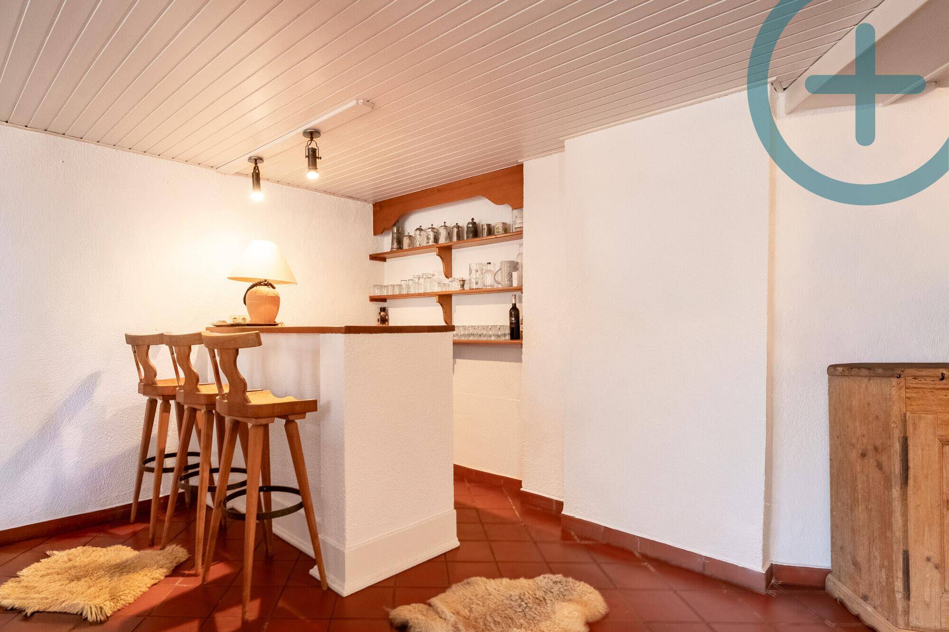Gemütlicher Barbereich im Keller mit Holzregalen und Terrakotta-Fliesenboden.