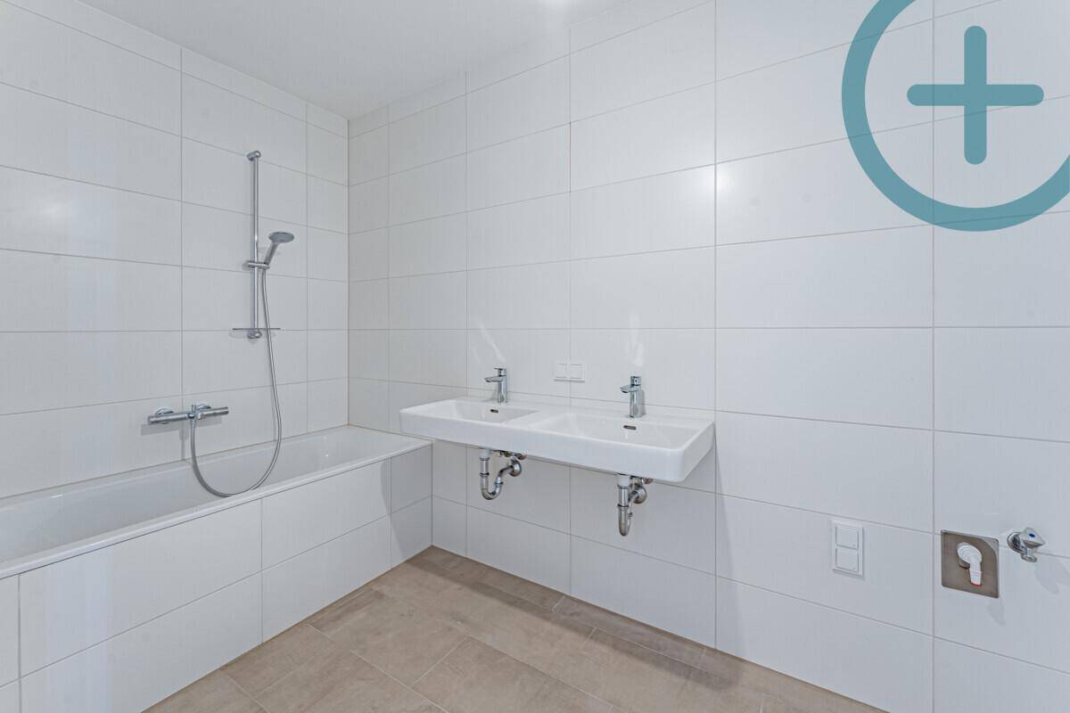 Modernes Badezimmer mit Badewanne, Doppelwaschbecken und weißen Fliesen.
