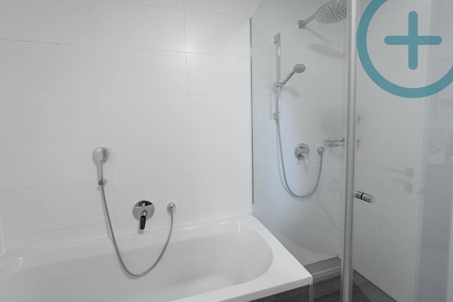 Modernes Badezimmer mit Badewanne und integrierter Duschkabine, komplett gefliest in Weiß.