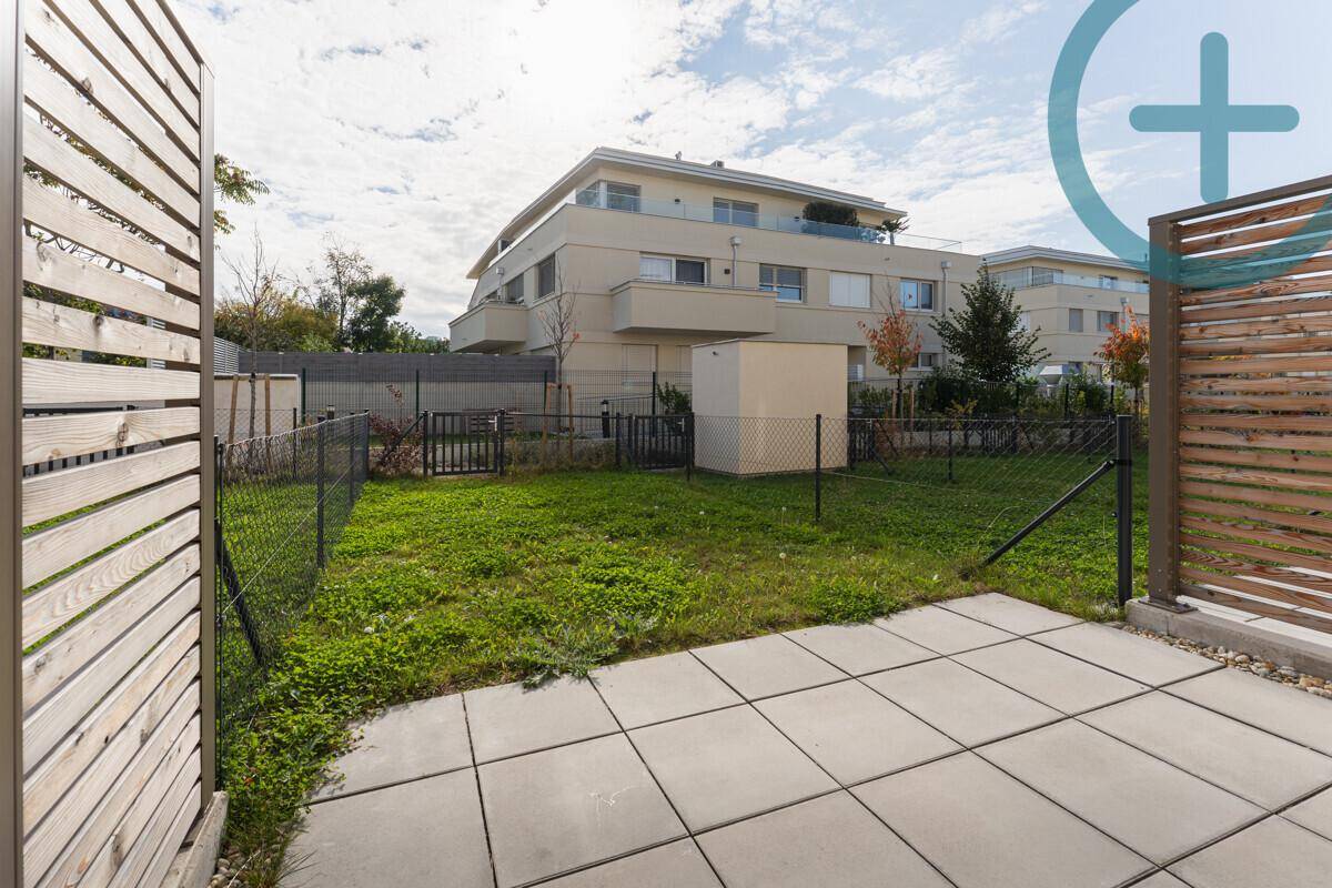 Private Terrasse mit gepflastertem Bereich und kleinem Rasenstück, umgeben von Zäunen.
