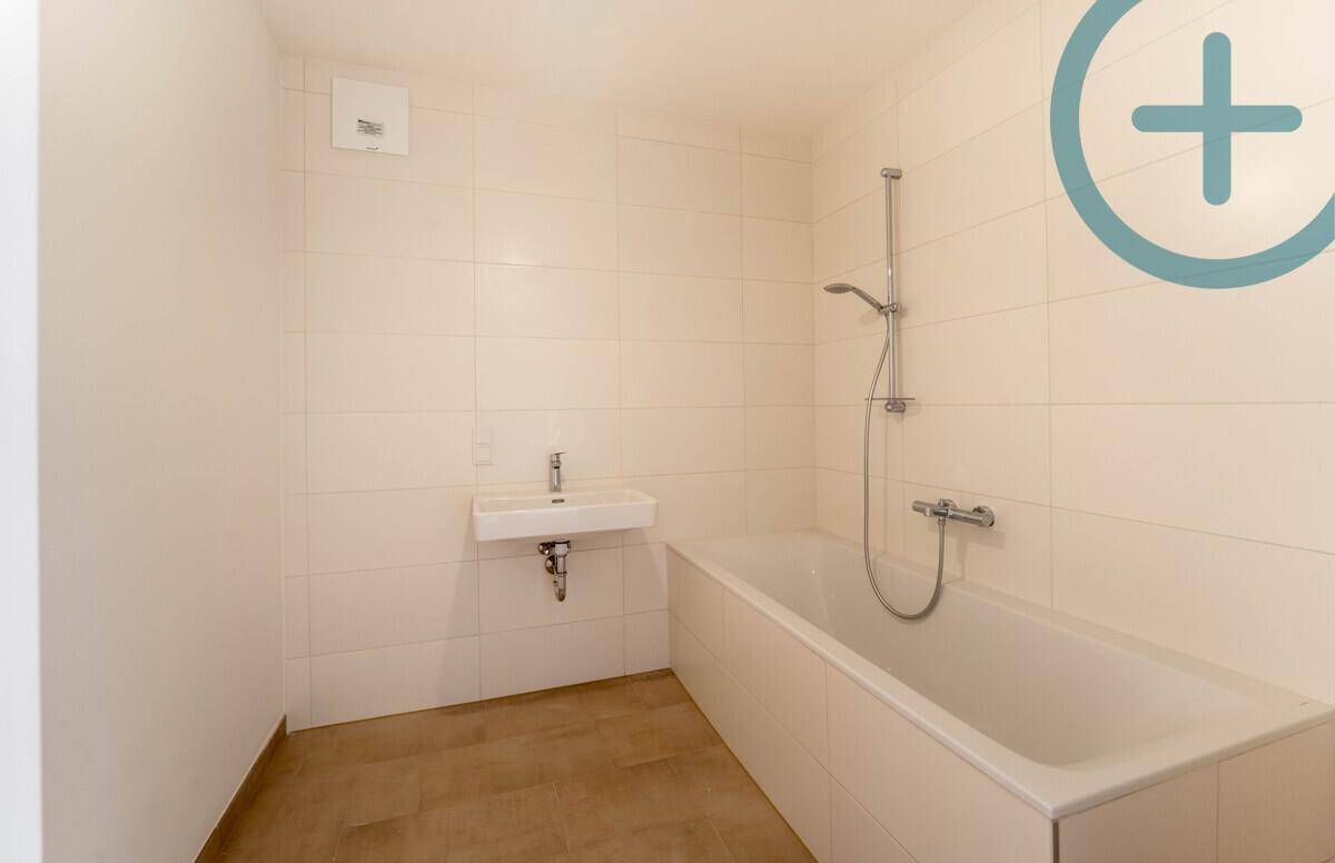 Modernes Badezimmer mit Badewanne, Wandwaschbecken und beheiztem Handtuchhalter in hellen Fliesen.