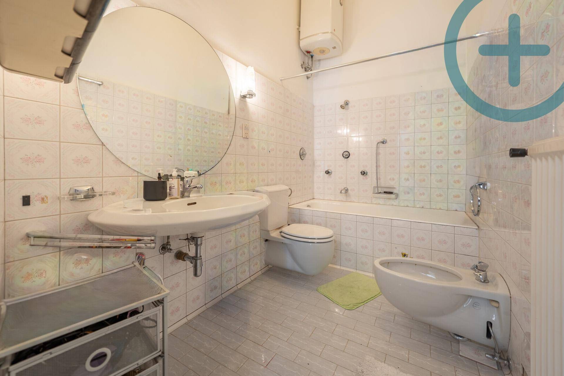 Badezimmer mit Badewanne, Bidet, WC und großem Spiegel über dem Waschbecken.