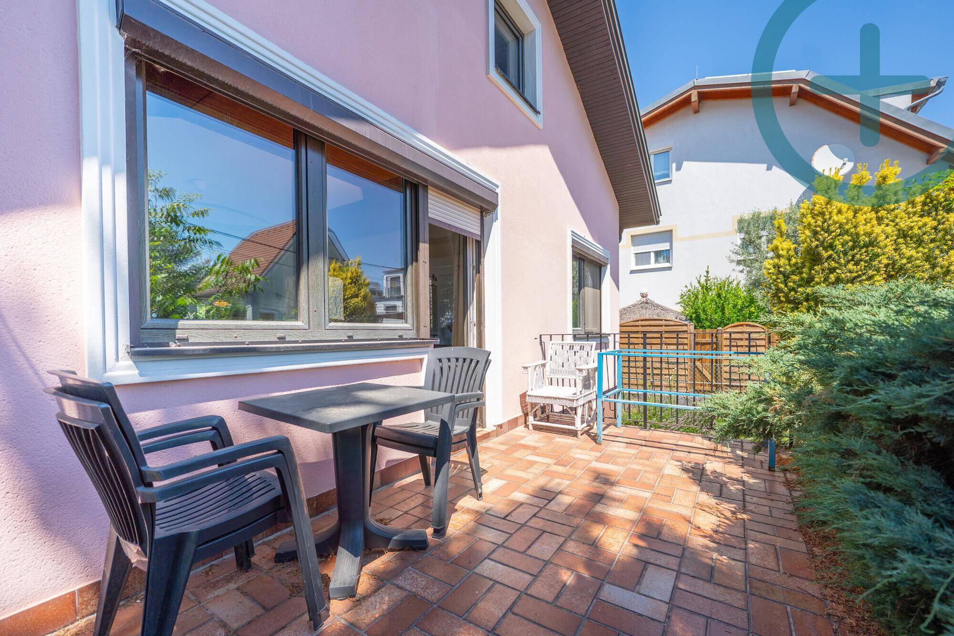 Kleine, gepflasterte Terrasse am Haus mit Gartenmöbeln und Blick auf die Umgebung.