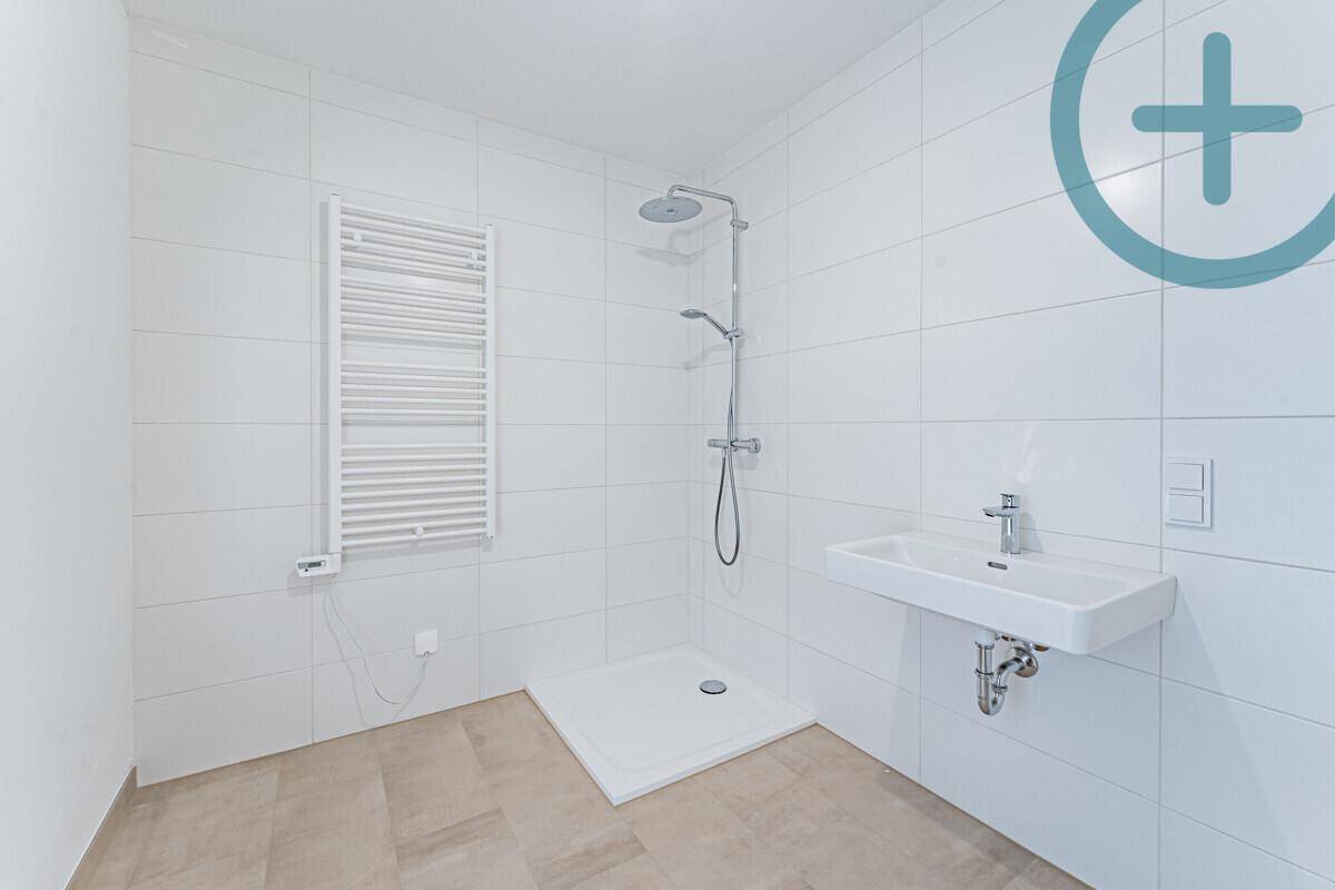 Modernes Badezimmer mit ebenerdiger Dusche, Handtuchheizkörper und Waschbecken.
