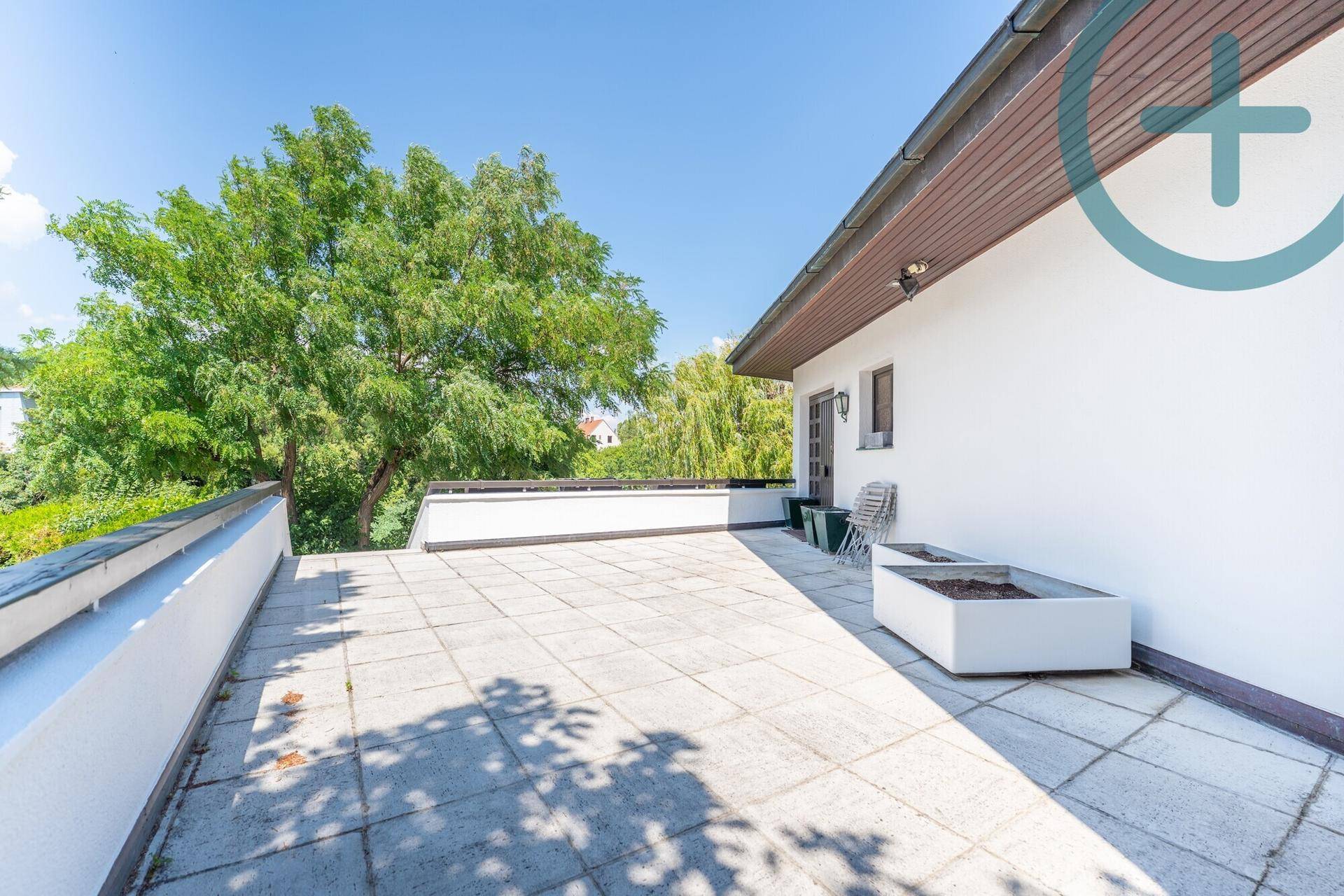 Geräumige, geflieste Terrasse im Obergeschoss mit weitem Blick auf die umliegende grüne Baumlandschaft.