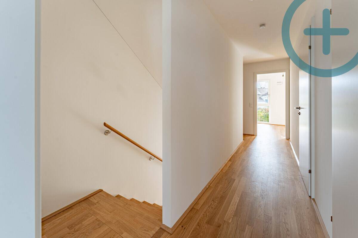 Heller Flur mit Holztreppe und Parkettboden, der zu weiteren Räumen führt.