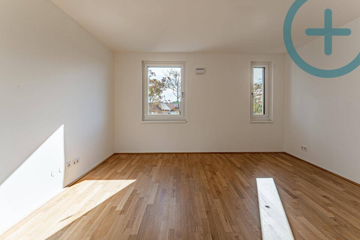 Geräumiges, helles Zimmer mit Parkettboden und zwei Fenstern, die viel Sonnenlicht hereinlassen.