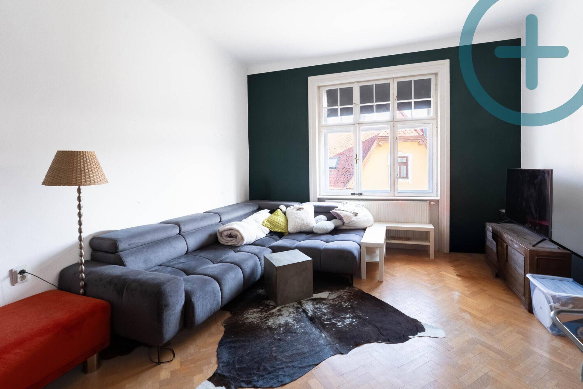 Geräumiges Wohnzimmer mit großem Ecksofa, Holzboden und einer dunklen Akzentwand.