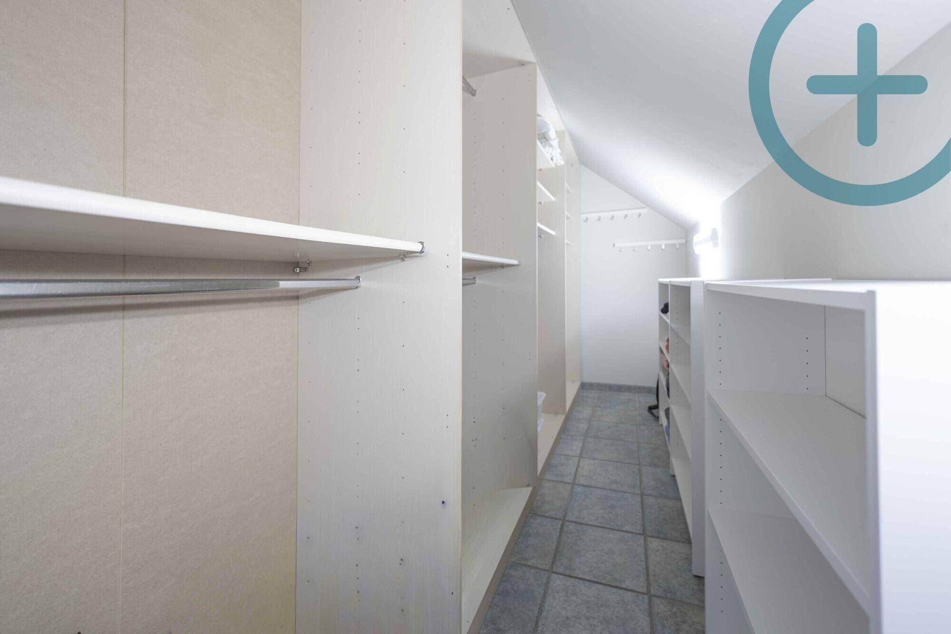 Praktischer begehbarer Kleiderschrank mit vielen Regalen und Stauraum unter der Dachschräge.