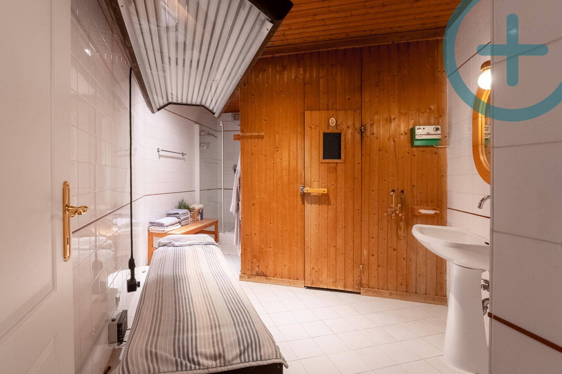 Privater Wellnessbereich mit Sauna, Duschkabine und Liege für Entspannung.