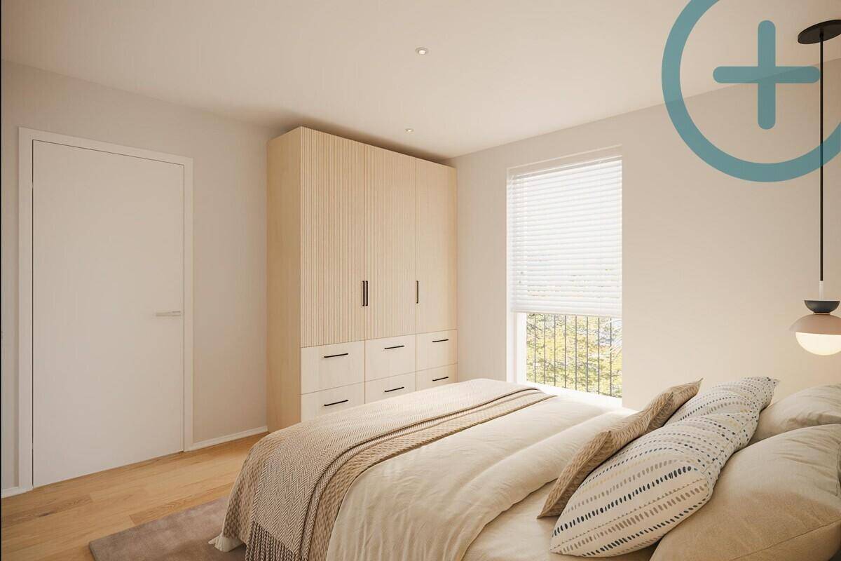 Schlafzimmer mit Einbauschrank, Holzboden und viel Tageslicht durch das große Fenster.