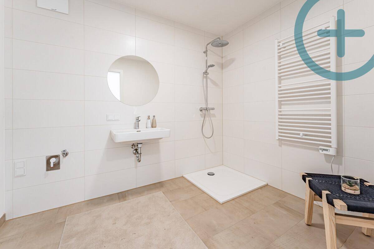 Modernes Badezimmer mit ebenerdiger Dusche, Einzelwaschbecken und Handtuchheizkörper.