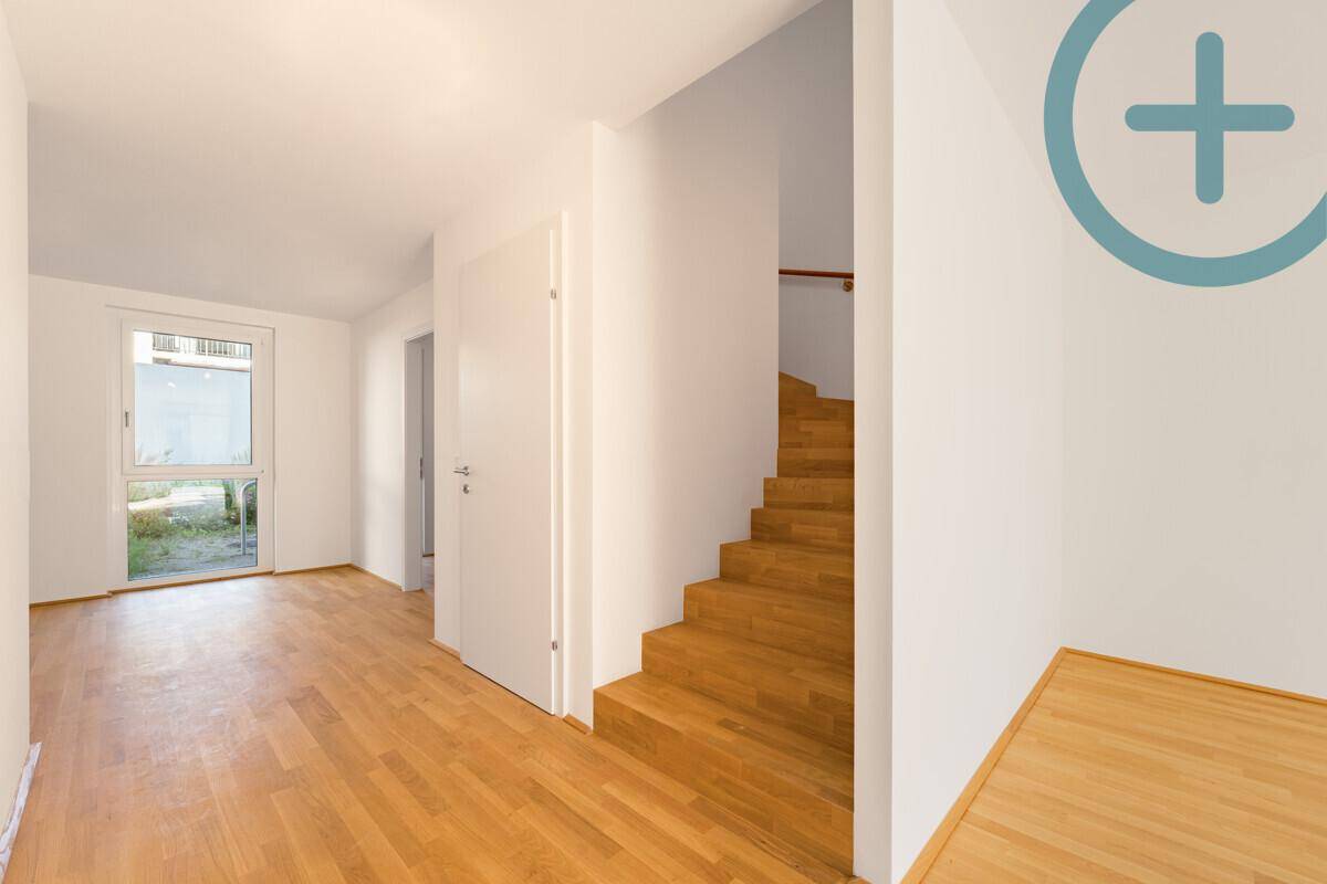 Heller Flur mit Holztreppe und Parkettboden, der zu den oberen Etagen führt.
