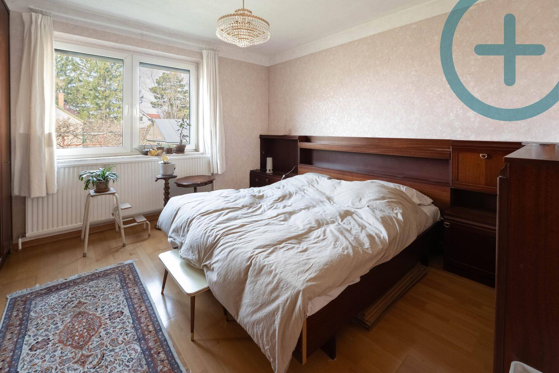 Geräumiges Schlafzimmer mit Parkettboden, Einbauschrank und Blick ins Grüne.