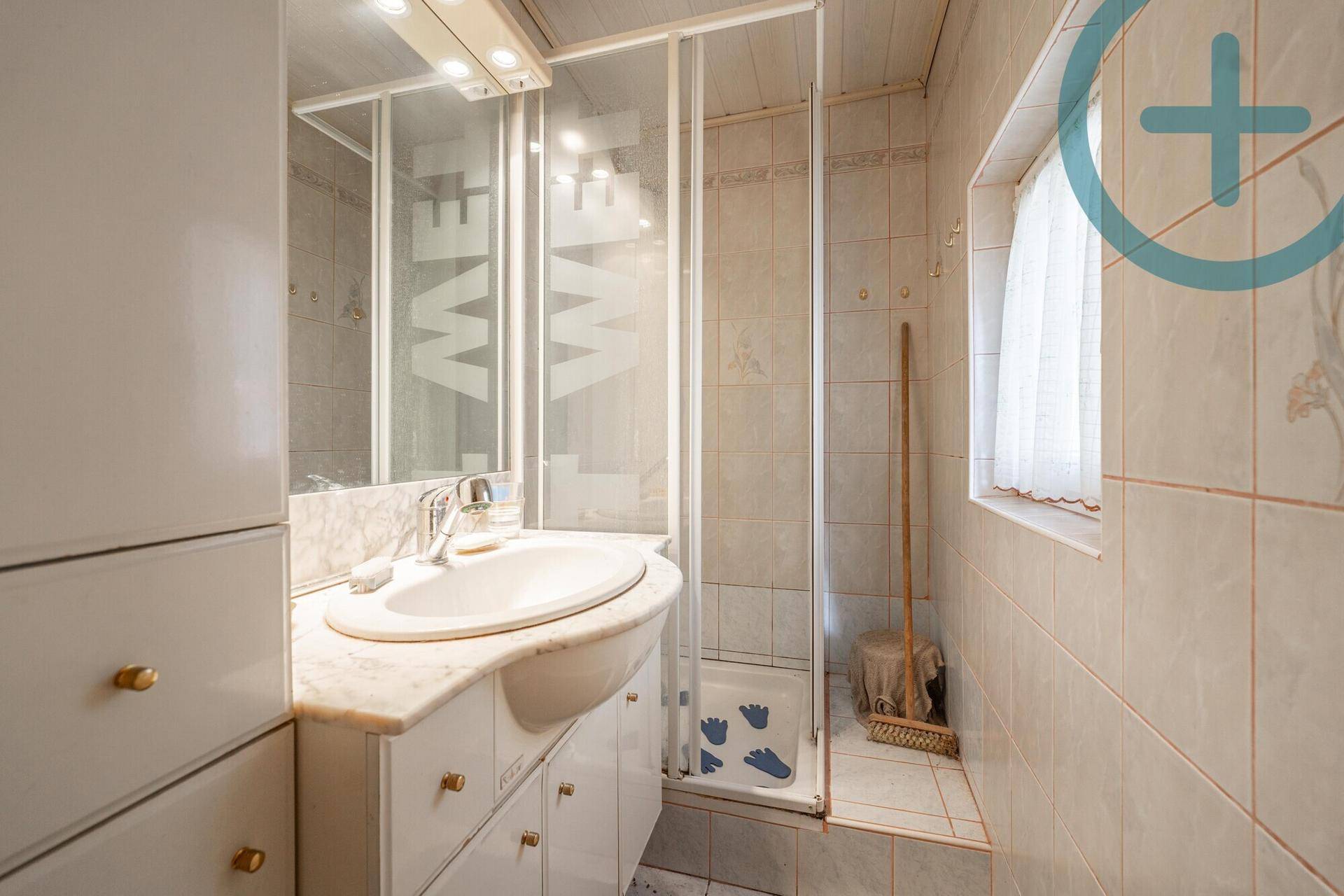 Kleines Badezimmer mit Dusche, Waschbecken und Spiegelschrank.