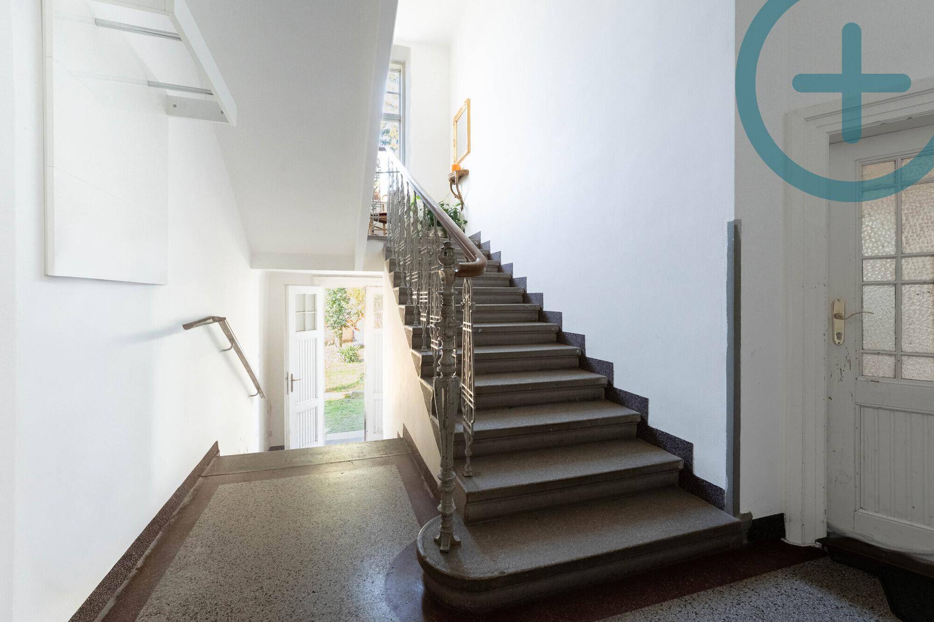 Geräumiges Treppenhaus mit historischem Geländer und Zugang zum Gartenbereich.