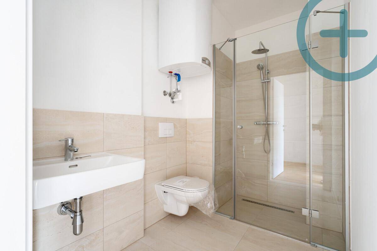 Modernes Badezimmer mit beigefarbenen Fliesen, wandhängendem WC und einer begehbaren Dusche.