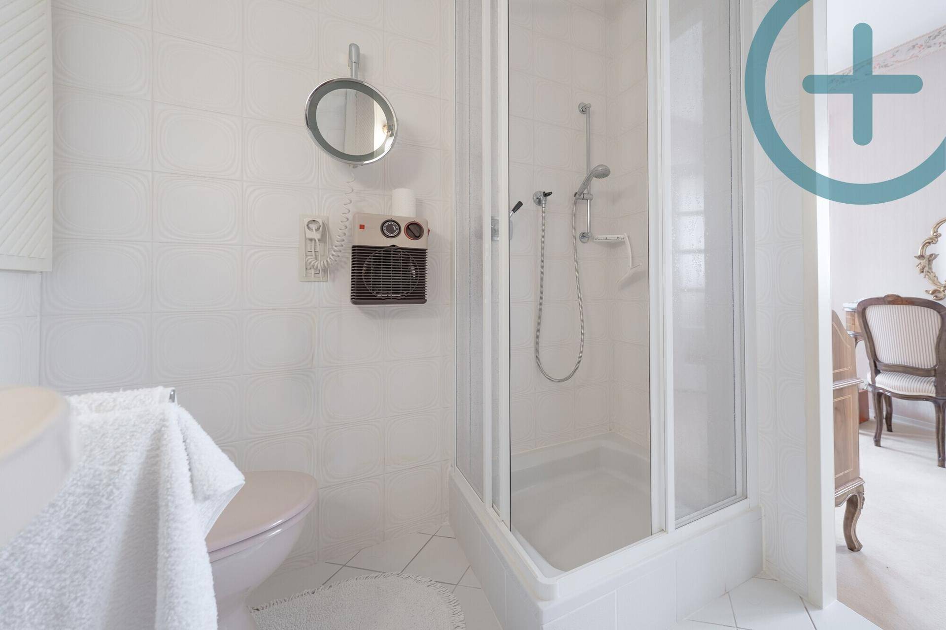 Helles Badezimmer mit Duschkabine, WC und weißem Fliesenboden.