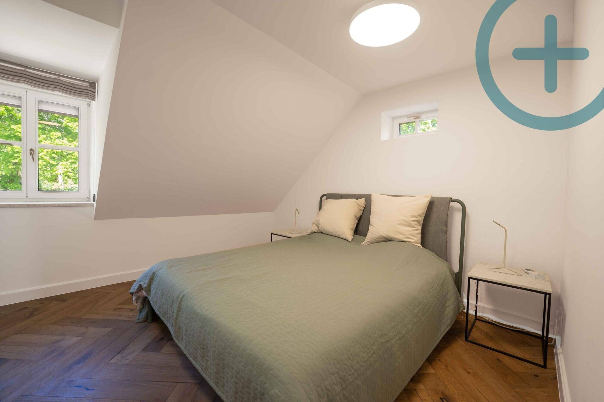 Gemütliches Schlafzimmer im Dachgeschoss mit schrägen Decken, Fischgrätparkett und Fenster.