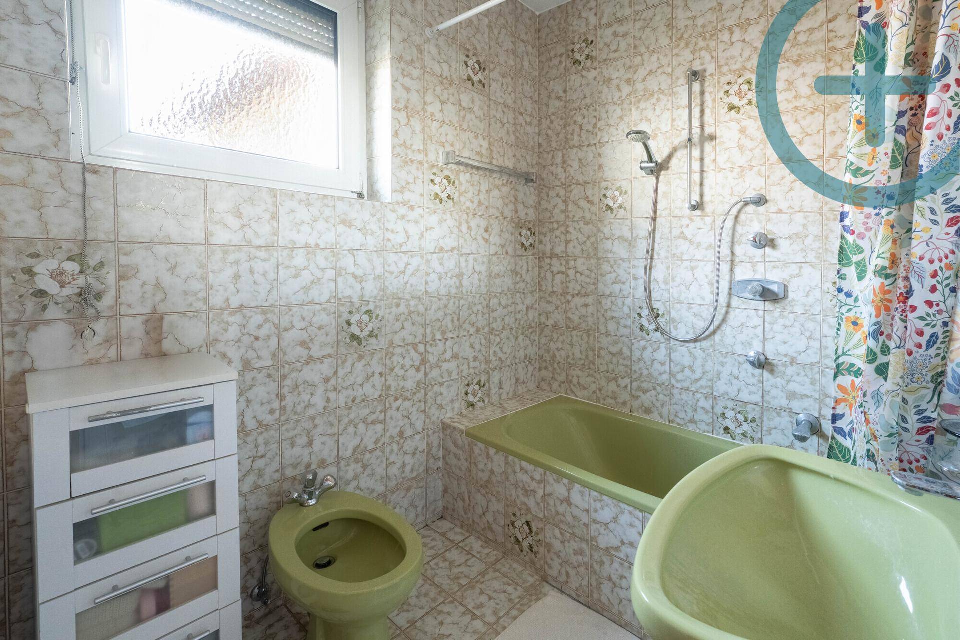Badezimmer mit grüner Badewanne, Bidet und Fliesen im 80er-Jahre-Stil.