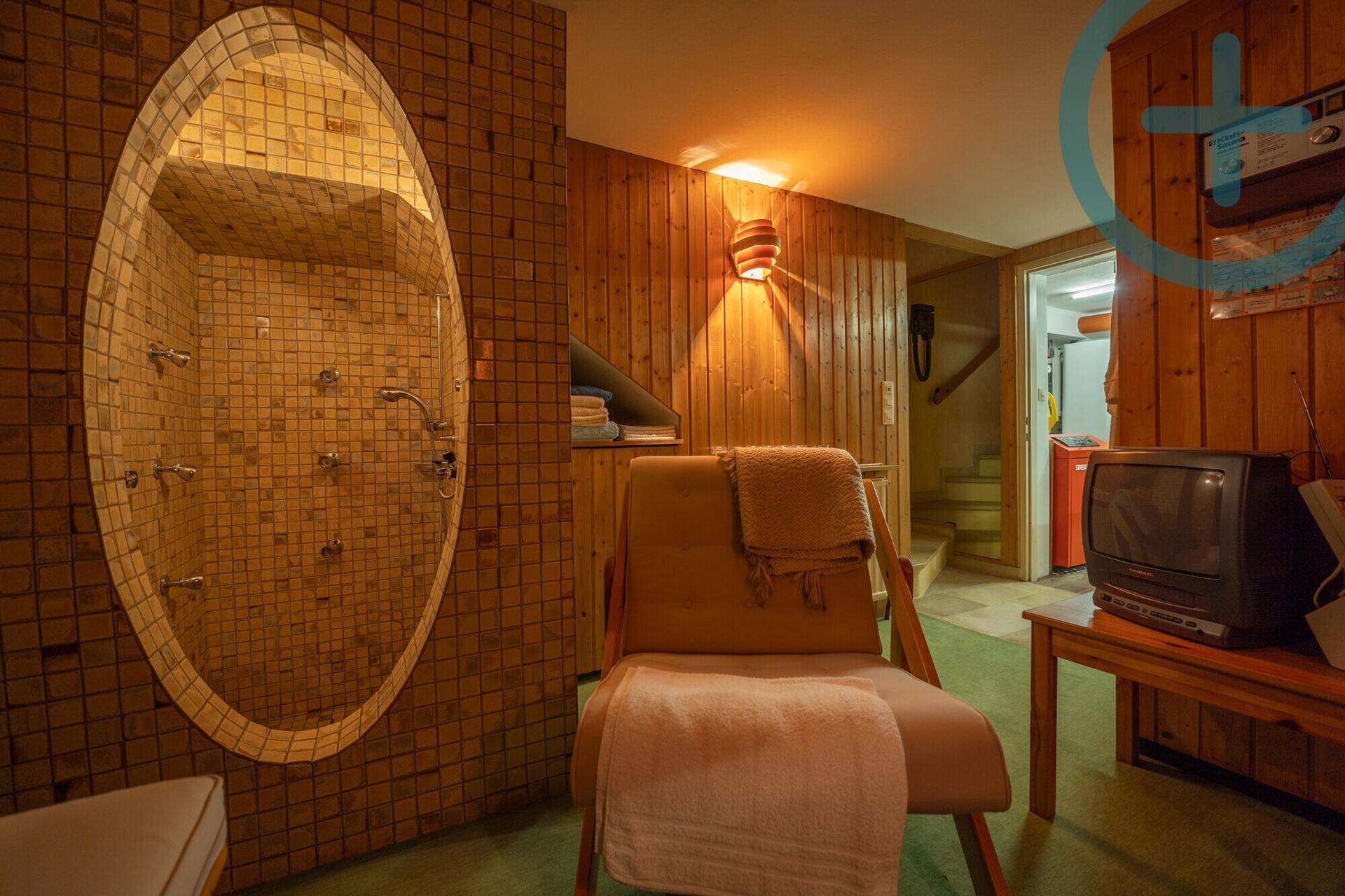 Rustikaler Wellnessbereich im Keller mit Mosaikdusche und Holzvertäfelung.
