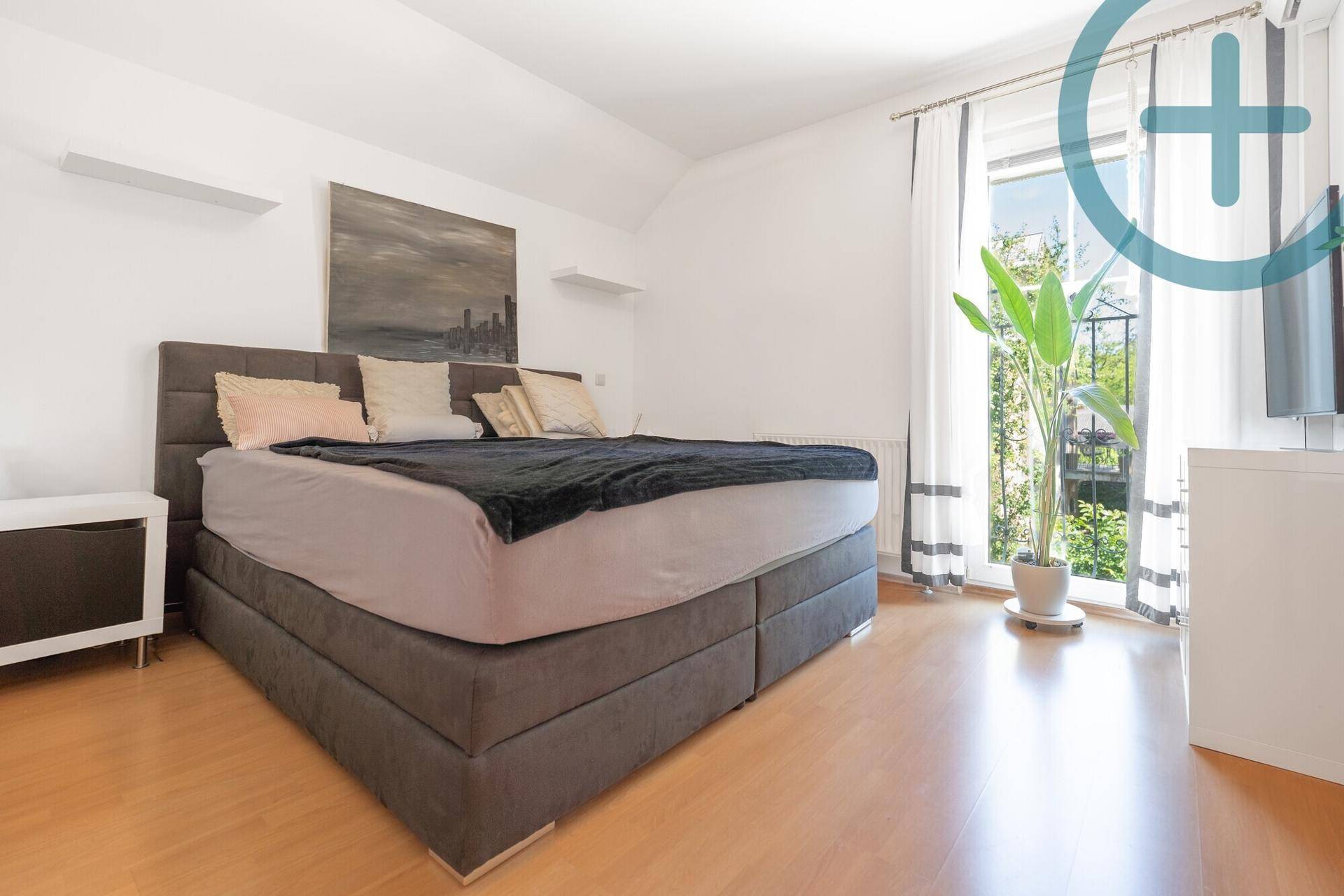 Geräumiges Schlafzimmer mit großem Bett, Parkettboden und Zugang zum Balkon.
