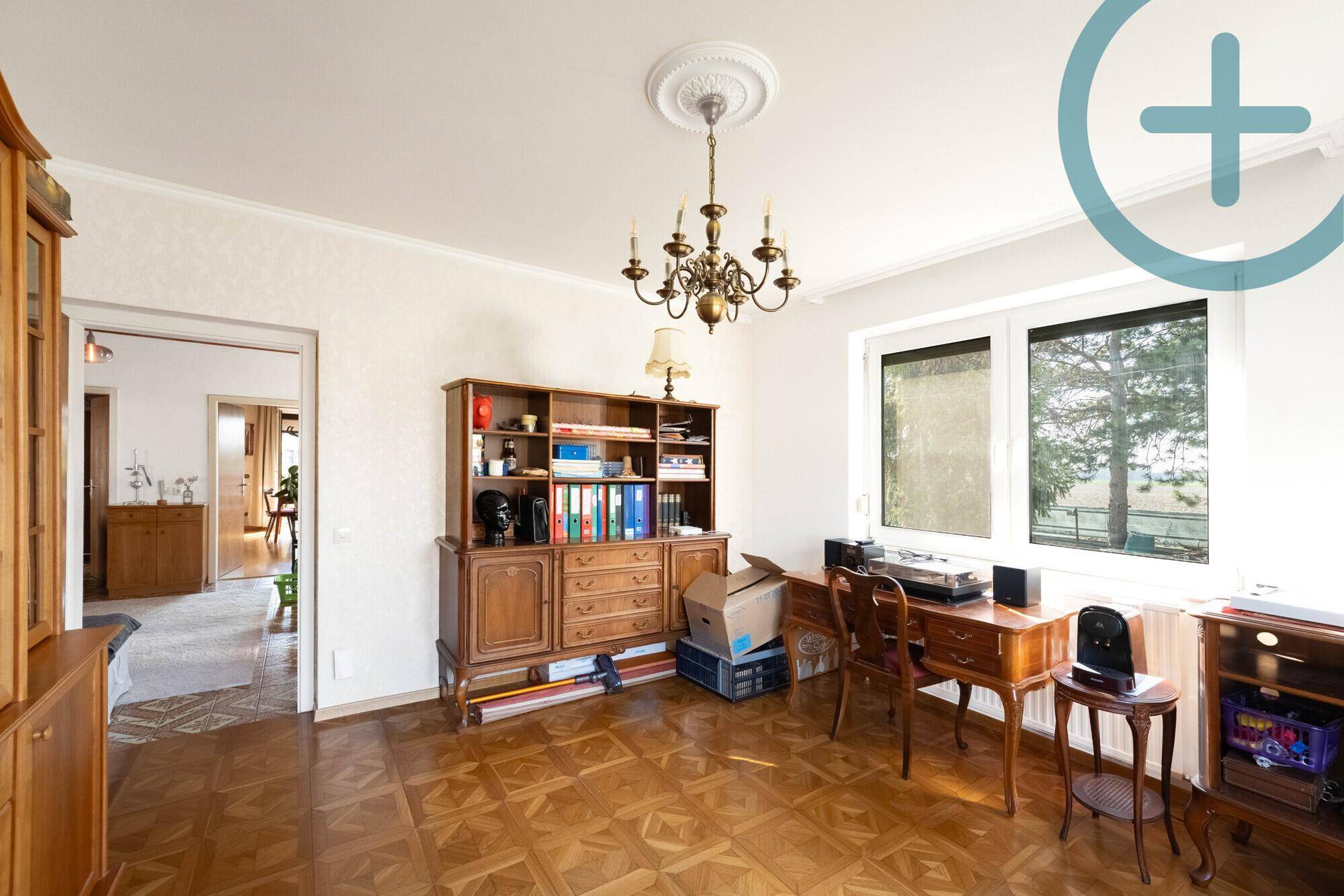 Geräumiges Wohnzimmer mit Parkettboden, antiken Möbeln und viel Tageslicht.