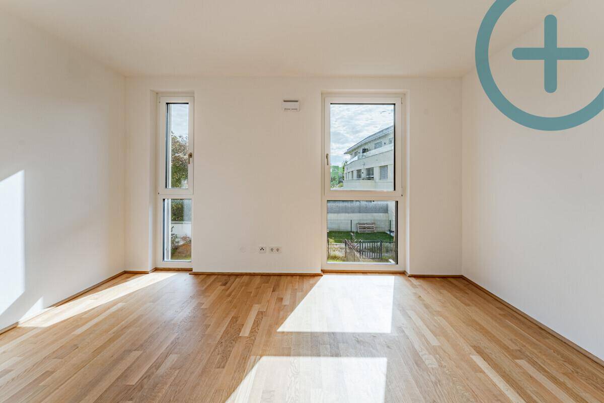 Lichtdurchflutetes Zimmer mit Parkettboden und großen Fenstern, ideal als Schlaf- oder Arbeitszimmer.