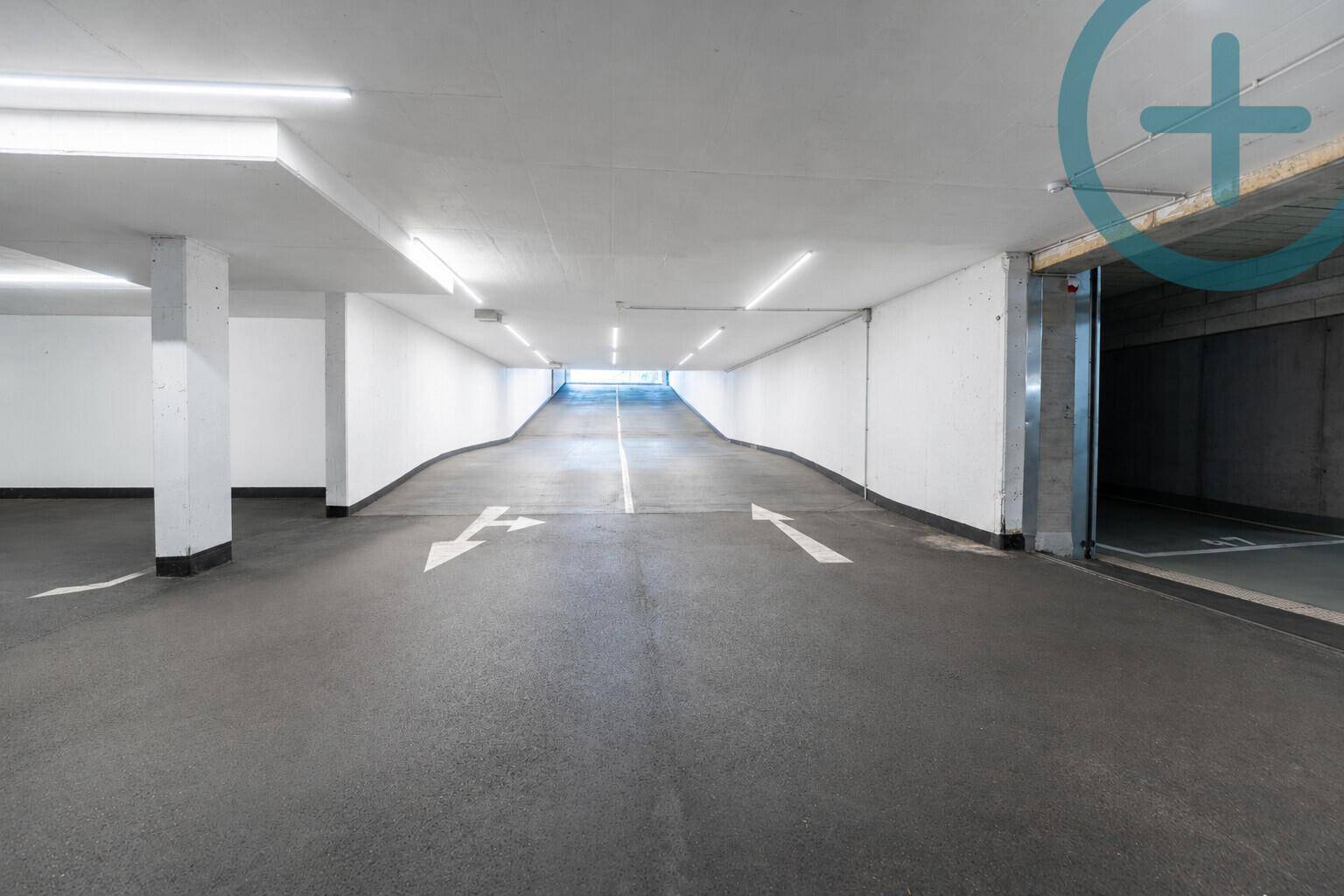 Zufahrt zur Tiefgarage mit heller Beleuchtung und klaren Fahrbahnmarkierungen.