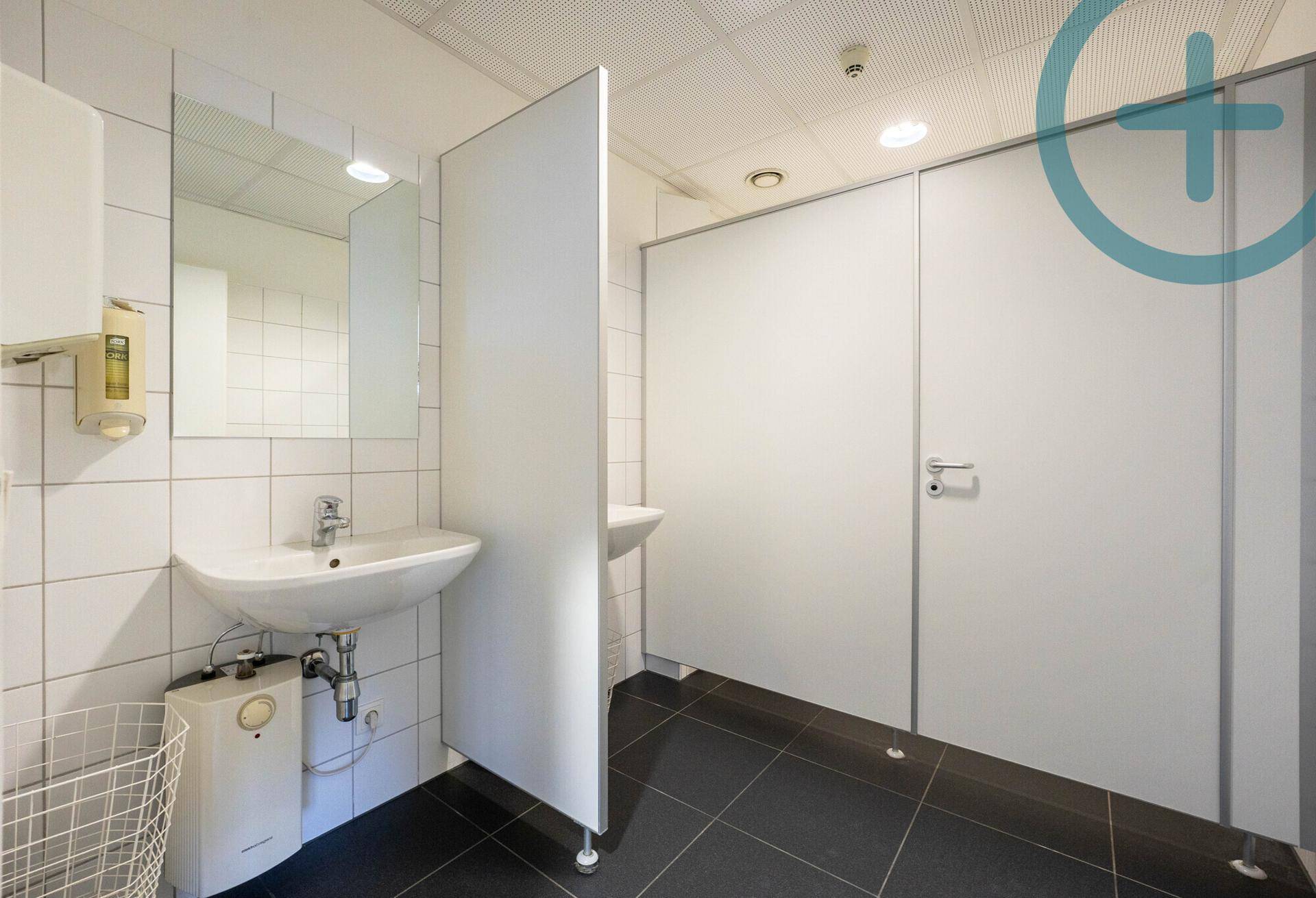 Sauberer und funktionaler Gemeinschaftswaschraum mit mehreren Waschbecken, Spiegeln und Toilettenkabinen.