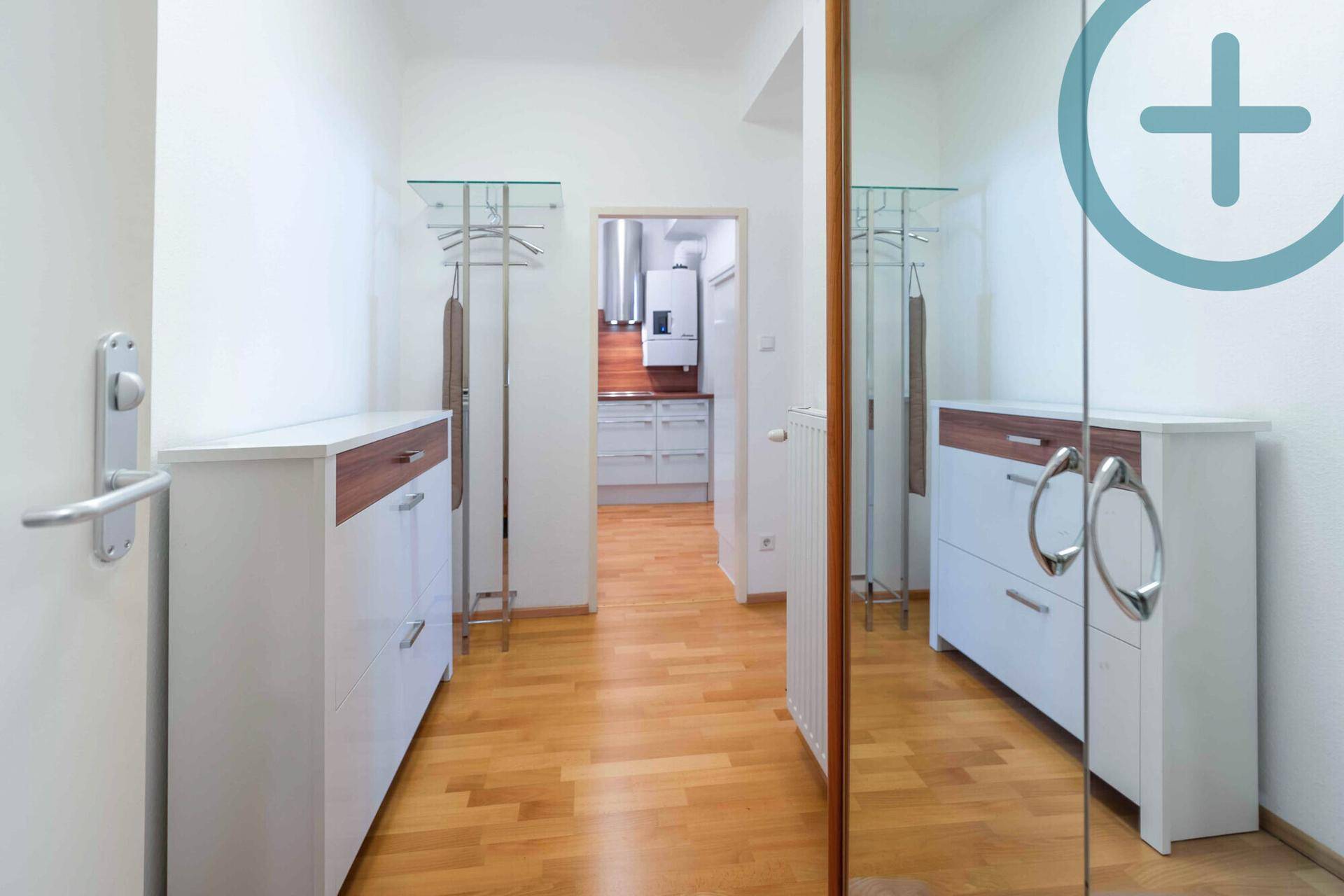 Heller Flur mit Garderobe, Schuhschrank und großem Spiegel, führt zur Küche.