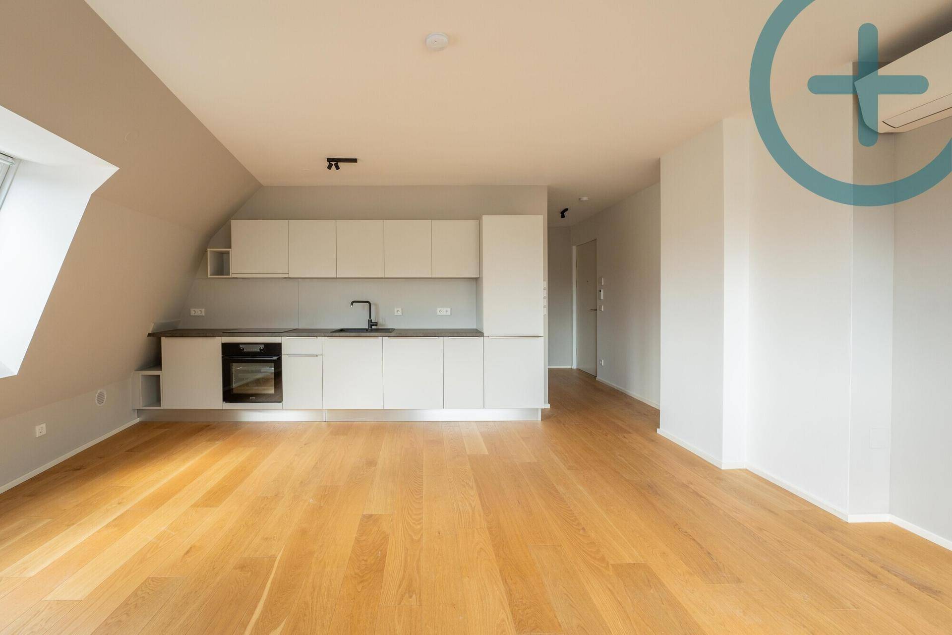 Moderne Einbauküche mit weißen Schränken, integriertem Backofen und Spüle in einem hellen Raum.