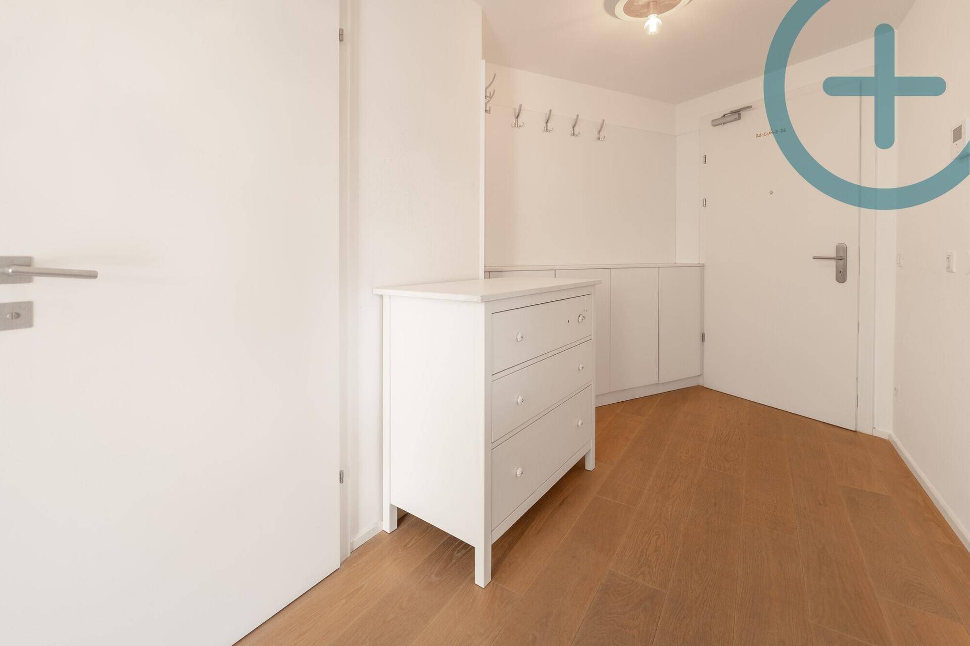 Heller Flur mit Holzboden, weißer Kommode und Garderobe im Eingangsbereich der Wohnung.