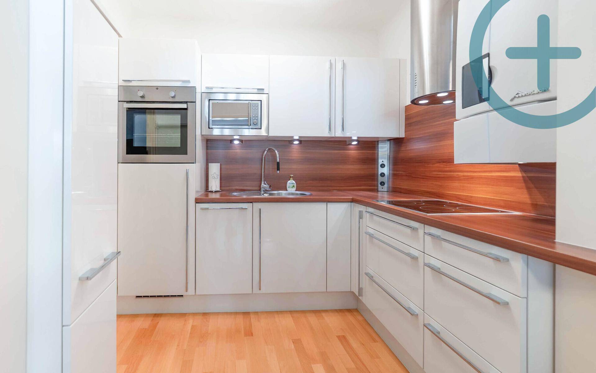 Moderne Einbauküche mit weißen Hochglanzfronten, Holzdetails und Edelstahlgeräten.