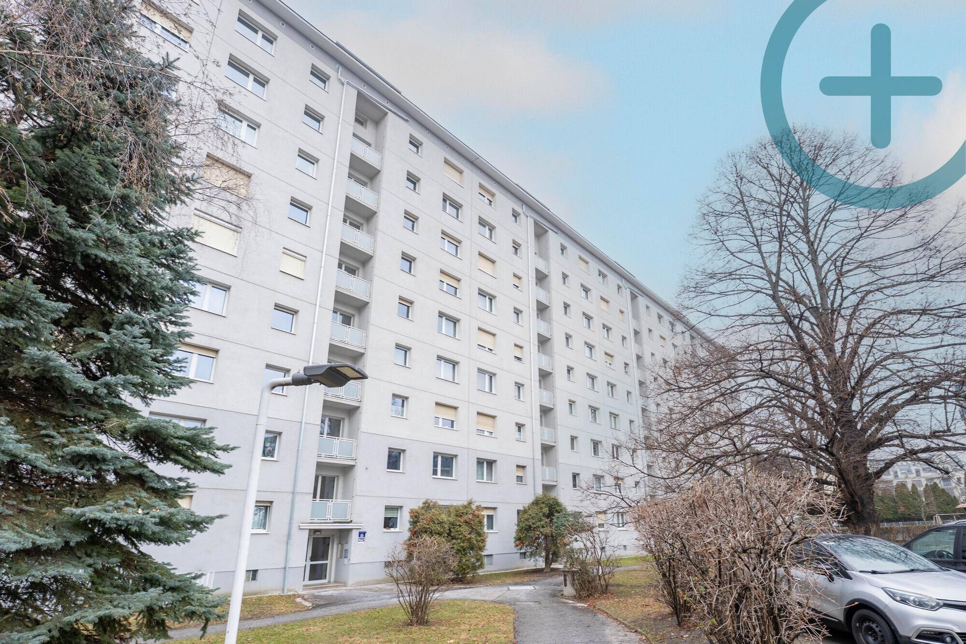 Großes Mehrfamilienhaus mit zahlreichen Balkonen und grüner Umgebung.