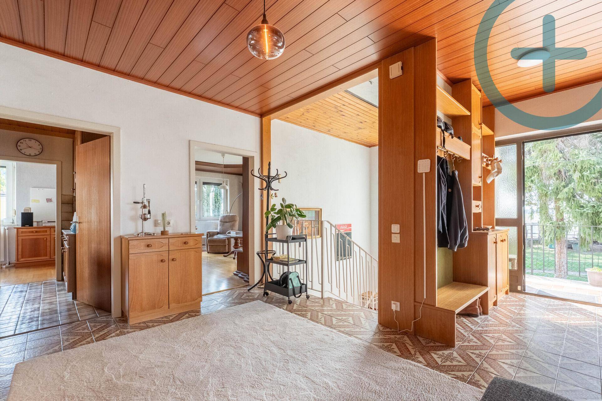 Heller Eingangsbereich mit Holzdecke, Fliesenboden und Treppenaufgang.