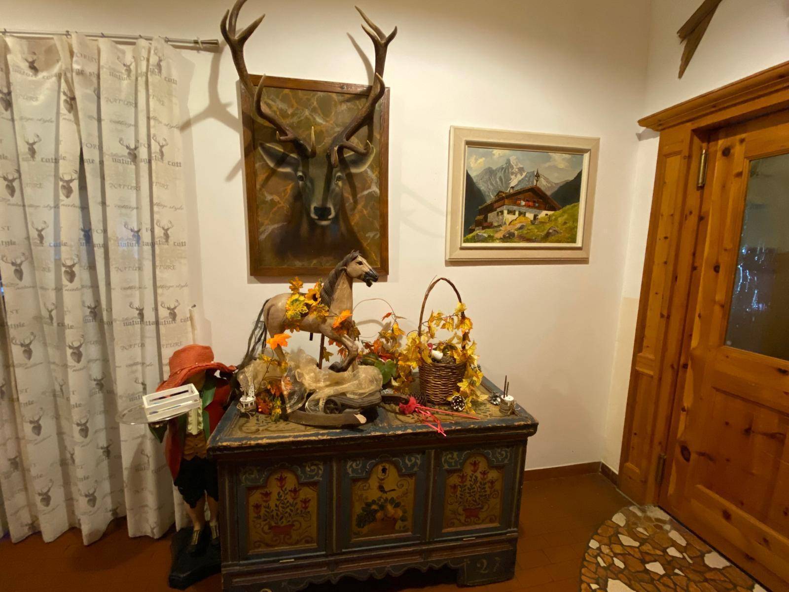 Detailansicht eines traditionellen Schranks mit Dekoration und Jagdtrophäen an der Wand.